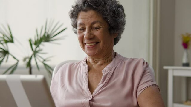 Using tablet. Cheerful Elderly black woman in afternoon enjoying online game at home.