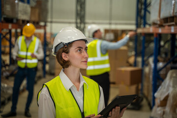 Warehouse employees reading a clipboard in a logistics centre,Warehouse worker taking packages for...