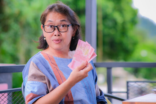A middle-aged woman showing some money happily