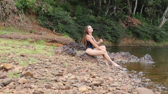 jovem mulher sexy de biquine em lazer de f&eacute;rias proximo a agua do rio 