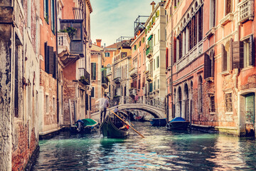 Canal in Venice, Italy with gondolier rowing gondola - obrazy, fototapety, plakaty