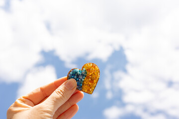 brooch in the shape of a heart in yellow-blue color against the sky. colors of the flag of Ukraine,...