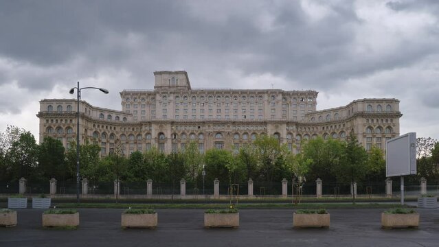 Side view of Palace of Parliament building with storm clouds timelapse during day, in Bucharest, capital of Romania. Landmark, politics, tourism, exterior.