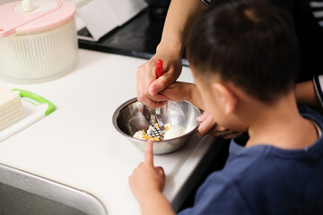 母親と一緒に卵サンドを作る男の子の後ろ姿