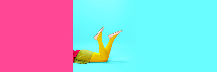 Female legs in yellow tights over vivid pink and blue background. Shopping, season sales. Pop art...