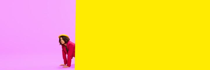 News, journalism. Young girl in stylish clothes peeking out vivid yellow and pink background. Pop art style. Concept of art, creative vision, fashion. Complementary colors. Banner. Copy space for ad