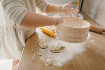 Little kid daughter having fun cooking pastries or pie on kitchen table top. Child knead dough, cooks pizza, bake cookies, dumplings, croissants for mother, father. Family preparation food on weekend.