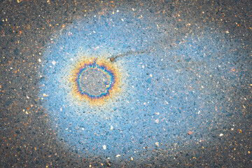 Fuel stain on wet asphalt. Colored stains from a gasoline leak on the road.