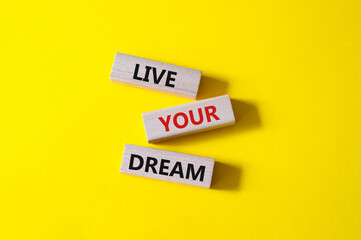 Live your Dream symbol. Wooden blocks with words Live your Dream. Beautiful yellow background. Business and Live your Dream concept. Copy space.