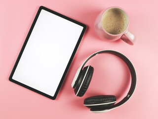 lat lay of white blank screen digital tablet, pink cup of coffee and headphones isolated on pink background