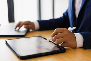 Asian male businessman in formal suit checking exchange rate of stock market with laptop computer hologram chart Business and financial success concept. Forex charts.