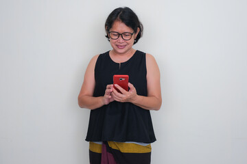 A woman in black is busy with her smartphone, smiling.