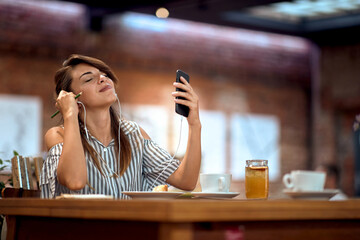 Young woman enjoying music in cafe, holding pen, feeling inspired.