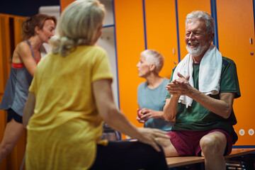 Group of four people in gym locker room, senior man and woman having a joyful conversation sitting facing each other.