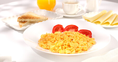 scrambled eggs with bacon and tomato. breakfast on a white plate. food on a sunny morning. fried eggs close-up.