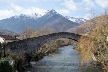 Fototapeta na wymiar Saint-Etienne-de-Baigorry, Pont Romain au Pays Basque qui passe au dessus de l'eau avec des montagnes en fond