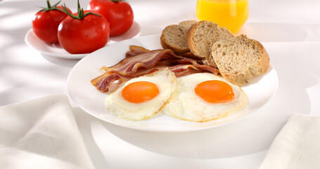 fried eggs with bacon on a plate. breakfast with fresh vegetables and bread on the table. sunny morning. country style. organic farm food