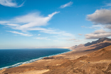 View Cofete beach on Jandia Peninsula in Fuerteventura, Canary Islands. Cofete beach is approximately 14 kilometers long with crystal clear turquoise waters, located in the Jandia Natural Park.