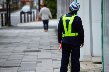街の工事現場で働く男性警備員の姿