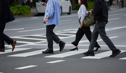 通勤時間の朝の交差点の横断歩道を渡る男女会社員の姿