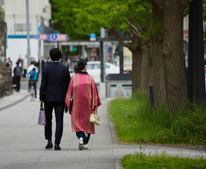 都市の街で歩く日本の伝統服を着ているカップルの姿