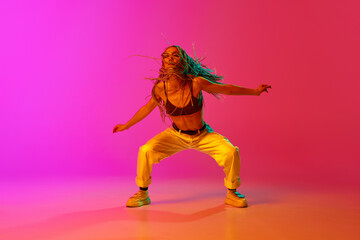 One young professional hip-hop girl wearing stylish clothes moving with inspiration over gradient...