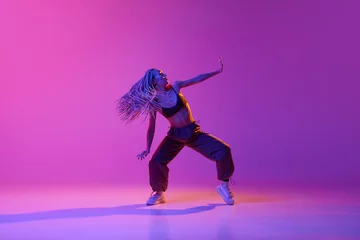 Foto op Plexiglas One young, attractive girl with dreadlocks dancing in street style over gradient purple neon background. Contemporary dance in motion © Lustre