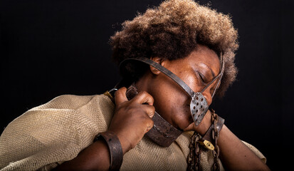 Face portrait of a black woman imprisoned with an iron mask on her face representing the slave Anastacia.