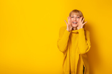 Beautiful woman shouting news on yellow color background