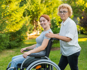 An elderly woman is carrying an adult daughter sitting in a wheelchair. Walk outdoors. 