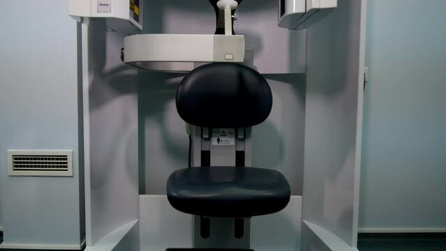 Modern digital panoramic X-ray dental equipment stands in dentist office. Comfortable chair for patient made of leather
