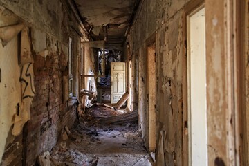 Desolate hallway with many doors full of debris