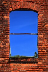 Window frame in brickwall with blue sky, the glass is molten due to a heavy fire