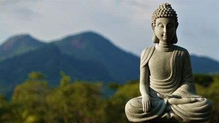 Obraz premium A stone Buddha in the lotus position meditates with his eyes closed – a statue of an Indian god. 