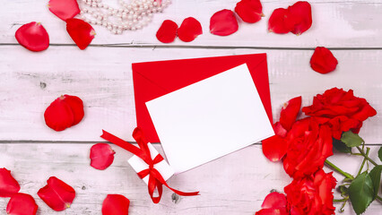 Bouquet of flowers red roses of the valley and empty paper sheet on wooden table from above, top view, copy space for text, flat lay