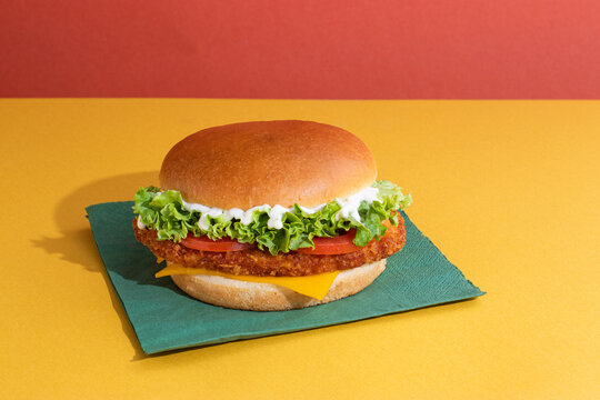 Fish burger with tomatoes, cheese slices and fresh lettuce
