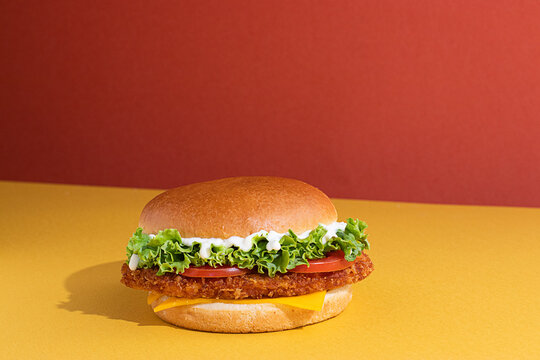 Fish burger with tomatoes, cheese slices and fresh lettuce