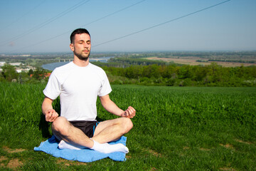 Fototapeta premium young man in meditation, a beautiful environment in nature for relaxation 