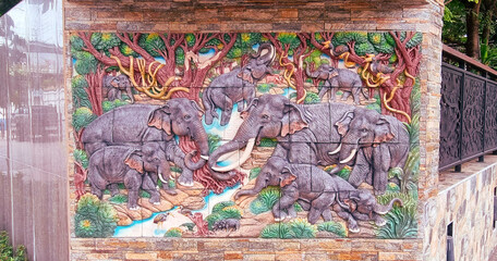 A beautiful raised mural on a wall in Bangkok of elephants. © Christian Bannard