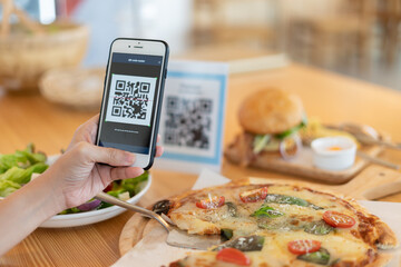 Woman use smartphone to scan QR code to pay in cafe restaurant with a digital payment without cash....