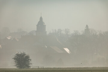 The church of Herleshausen in the morning fog - Powered by Adobe