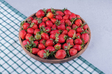 Bowl of strawberries on napkin, Fresh strawberries in plate on table, Heap of fresh strawberries in ceramic bowl, Top view fresh strawberry in wrought plate on concrete board, Fresh juicy strawberry.