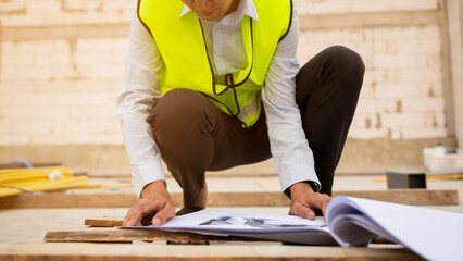 An Asian Engineering man wearing safety helmet analyzing construction drawings in construction site