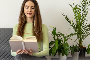 A happy, beautiful young woman with long hair and a book in her hands, reading