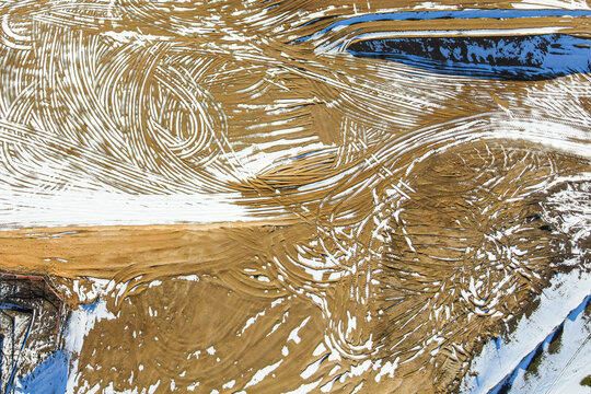 Aerial view of a construction site with tractor tracks in the dirt
