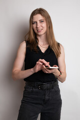Portrait of young pretty businesswoman, with mobile phone, standing over white background
