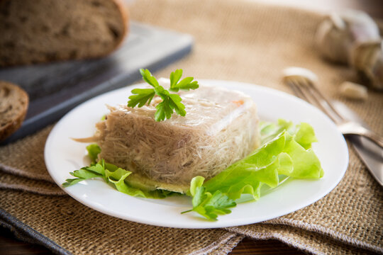 Boiled chicken meat aspic in meat gelatin broth in a plate