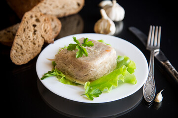 Boiled chicken meat aspic in meat gelatin broth in a plate