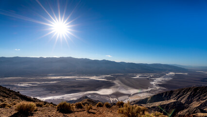 Bright sun setting over the Badwater Basin and the Amargoza River in the Black Mountains viewed from Dantes View in Death Valley, California, USA