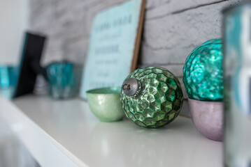Green glass balls and a small bowl as decoration on a white wooden shelf

